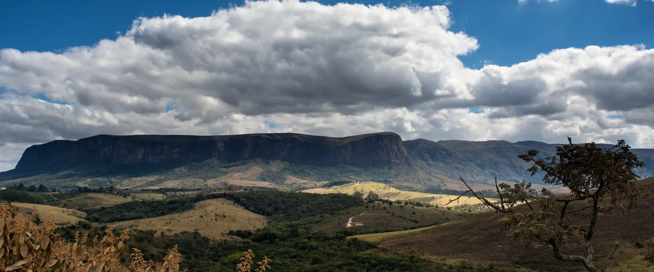 Paredão da Serra da Canastra sob nuvens, com campos em primeiro plano